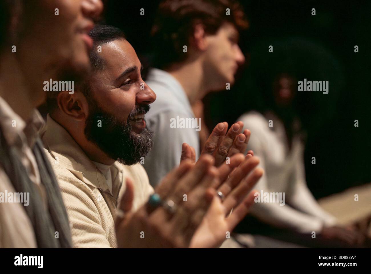 Happy bearded man clapping while enjoying play in stage theater Stock Photo