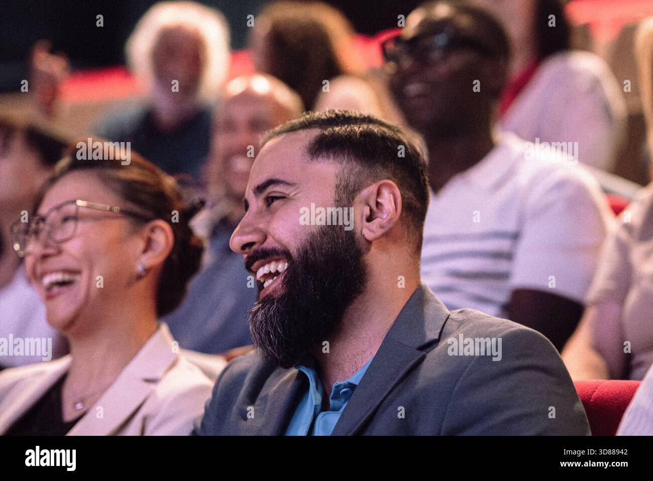 Happy bearded man enjoying stage play in theater Stock Photo