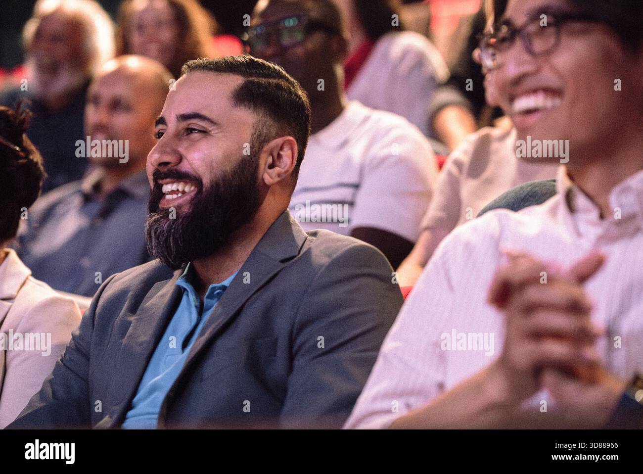 Happy bearded man enjoying stage play while sitting in theater Stock Photo