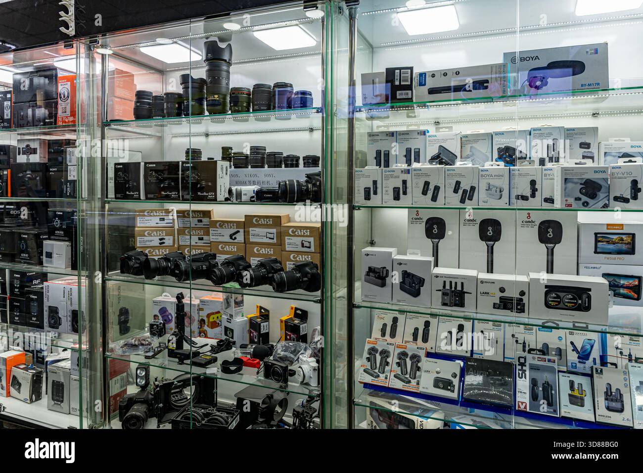18 NOVEMBER, 2025 - Tashkent, Uzbekistan: A showcase filled with various cameras, lenses, and audio accessories in an electronics store. The shelves are organized with multiple brands and products. Stock Photo