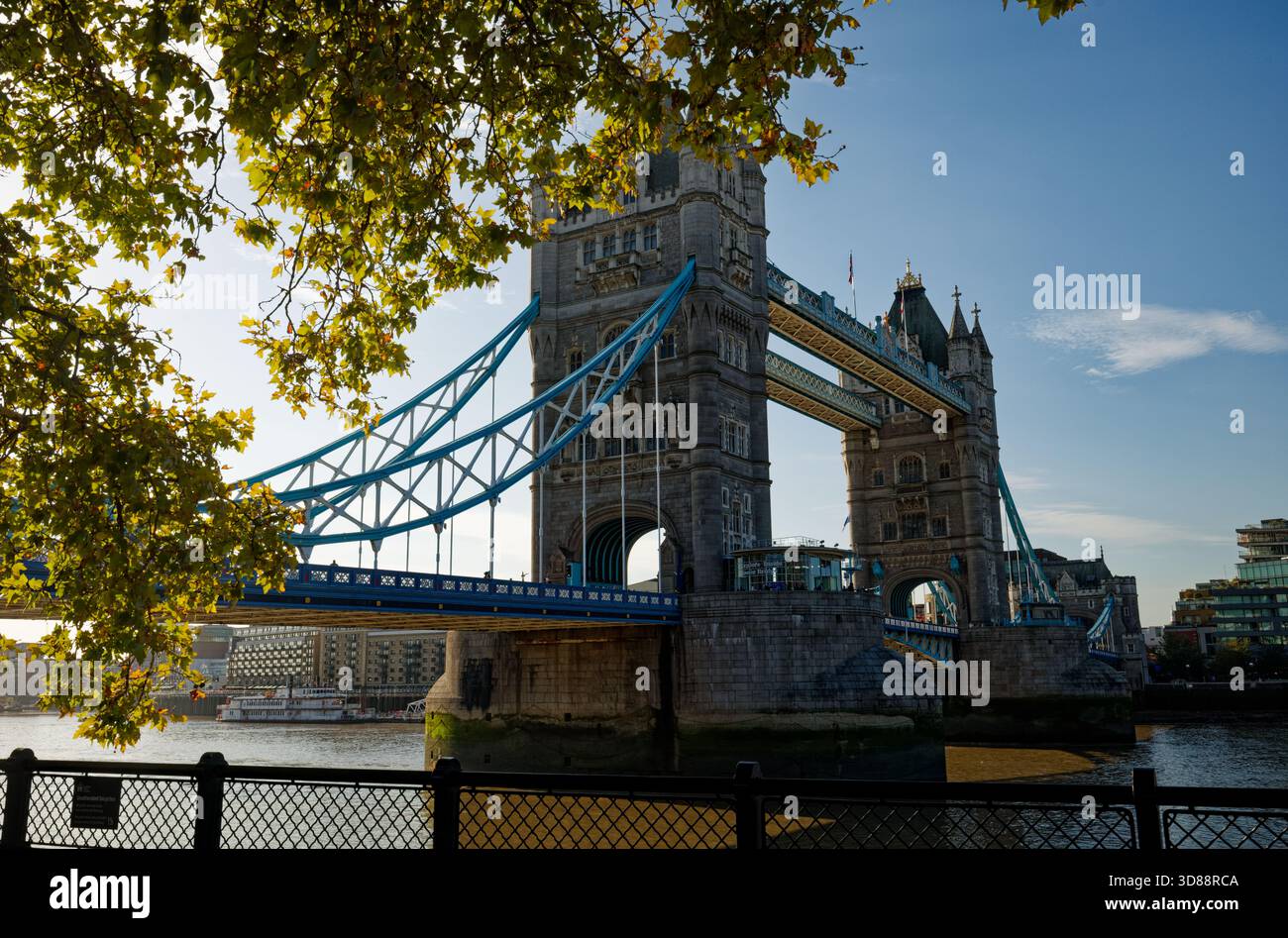 The iconic Tower Bridge over the River Thames on a sunny morning framed by trees, London, England. Stock Photo