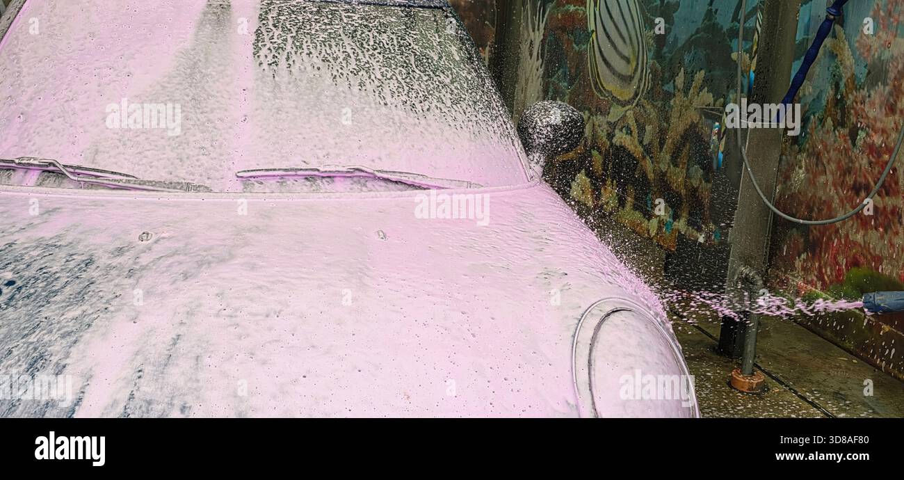 Berlin, Germany - May 18, 2025: Car wash scene featuring pink foam covering vehicle in bright outdoor environment. - Smartphone Captured Stock Image