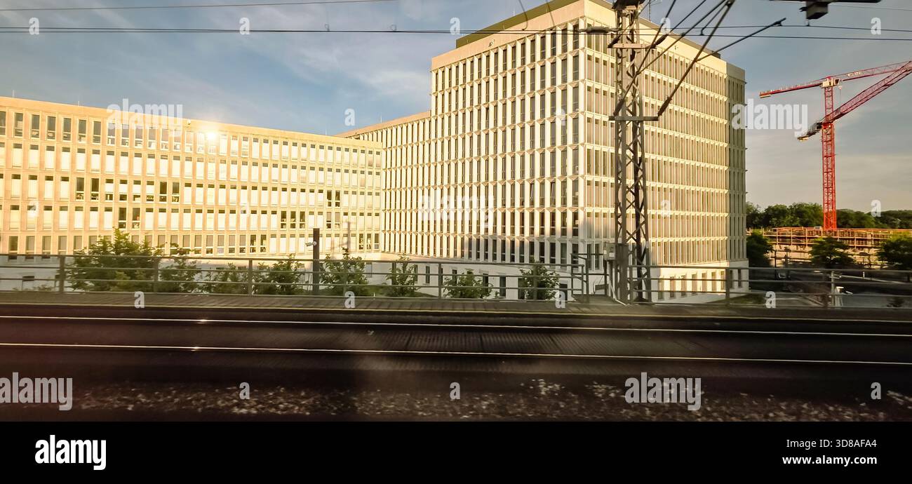 Berlin, Germany - June 13, 2025: Modern office structure features reflective glass facade and nearby construction crane. - Smartphone Captured Stock Image