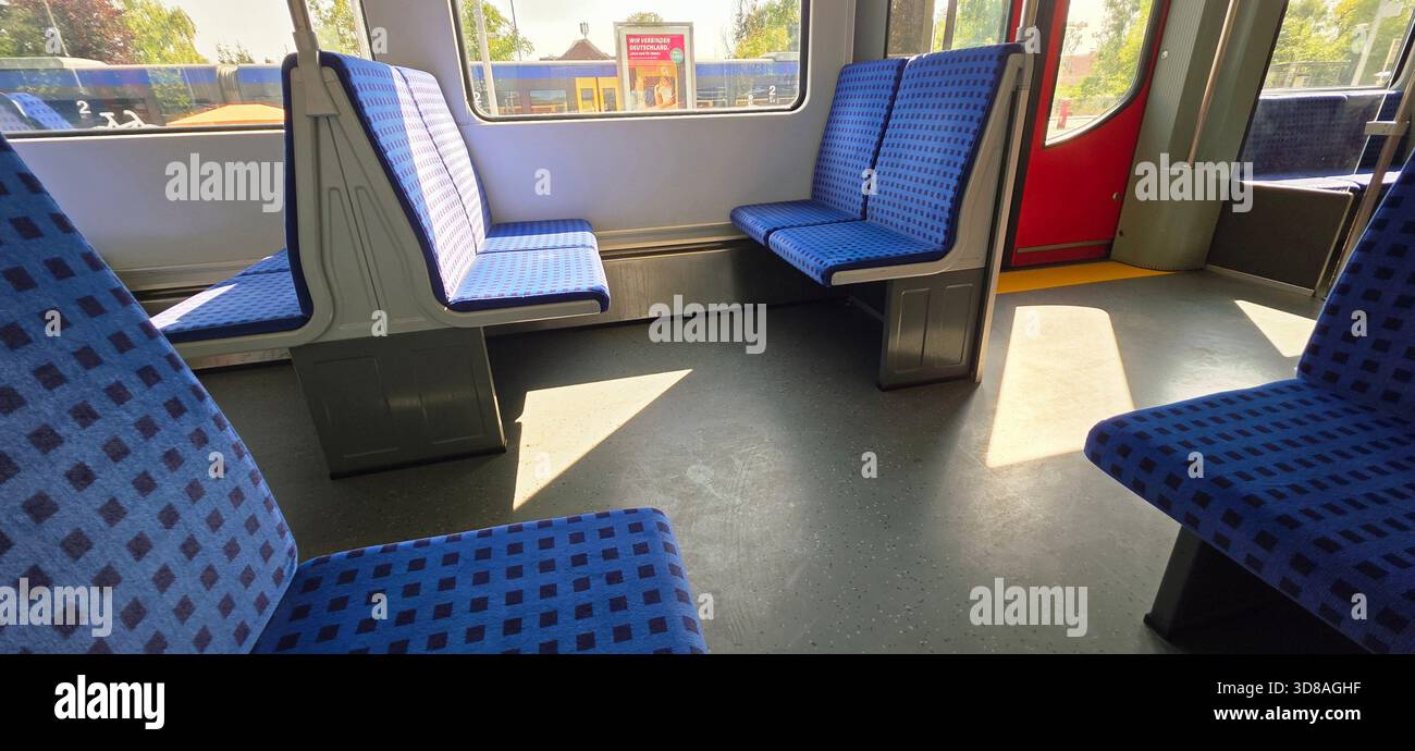Berlin, Germany - August 27, 2025: . Interior view of an empty train carriage featuring blue patterned seats and sunlight streaming in - Smartphone Captured Stock Image