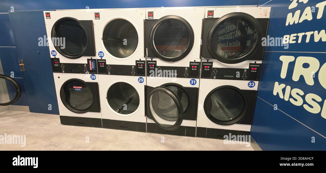 Berlin, Germany - September 25, 2025: Modern laundry machines are arranged in a self-service laundromat with a clean design. - Smartphone Captured Stock Image
