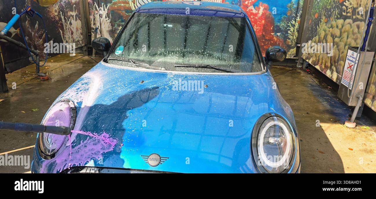 Berlin, Germany - September 27, 2025: Mini Cooper is being washed at a car wash with vibrant underwater mural. - Smartphone Captured Stock Image