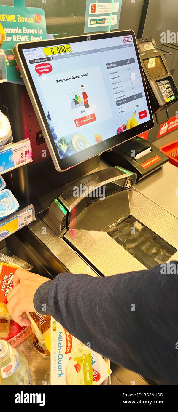 Berlin, Germany - September 27, 2025: User is scanning groceries at self-checkout kiosk in busy supermarket. - Smartphone Captured Stock Image