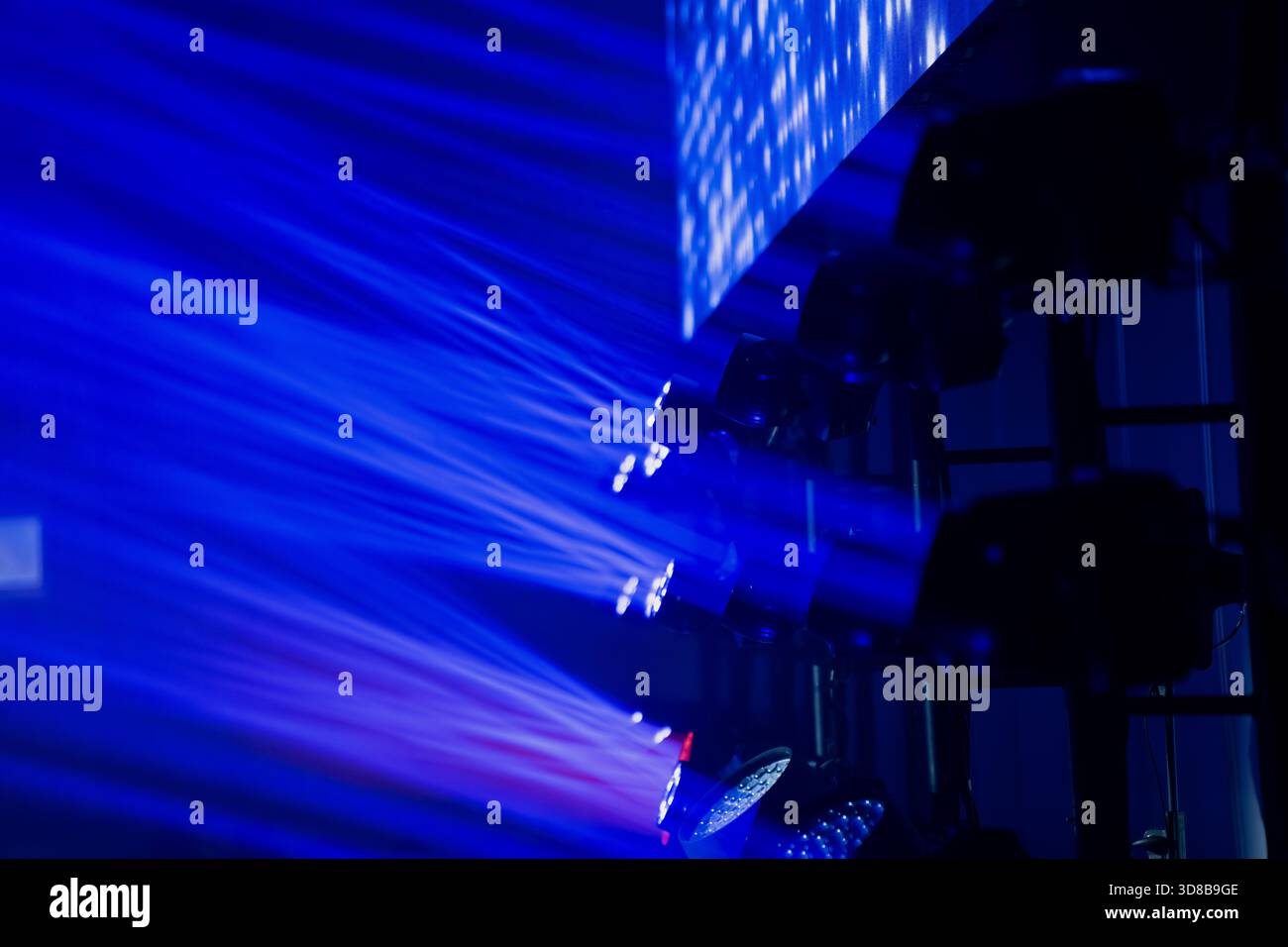 Moving head LED stage fixtures projecting intense blue beams across professional rigging, showcasing advanced entertainment lighting technology used i Stock Photo