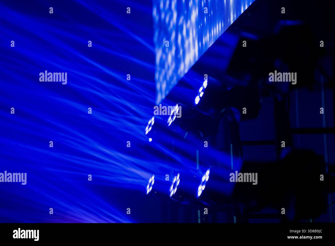 Moving head LED fixtures projecting concentrated blue beams toward a reflective screen, demonstrating advanced lighting technology used in modern even Stock Photo