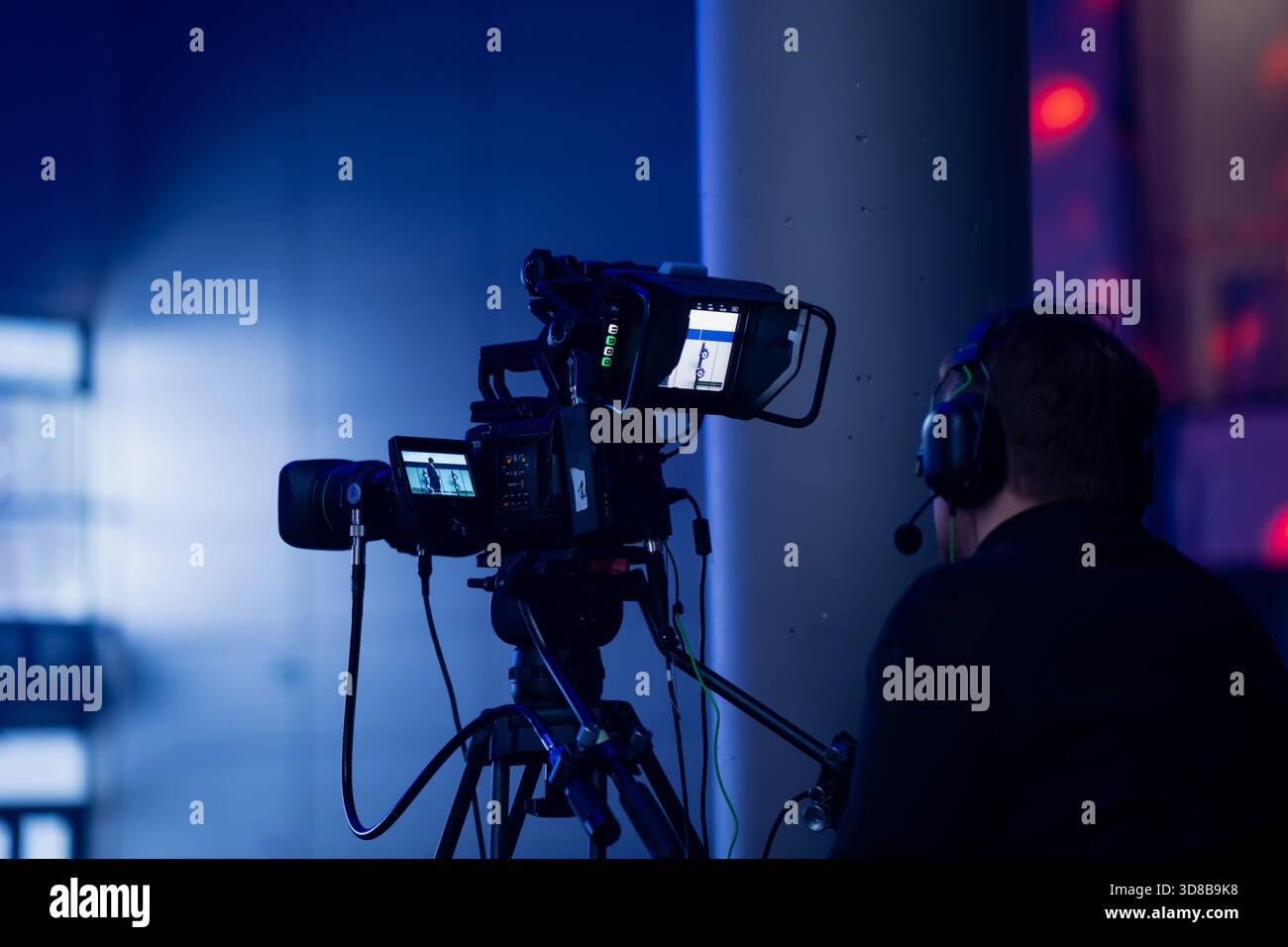 Camera Operster Broadcast camera operator filming a live indoor event using a ...