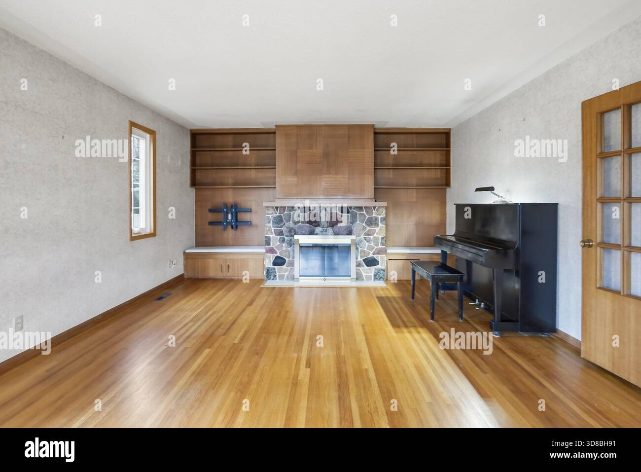 Large empty living room with a fireplace and a piano. The room is very  clean and empty, with no furniture or decorations. The fireplace is made of  sto Stock Photo - Alamy, image size:1300x957