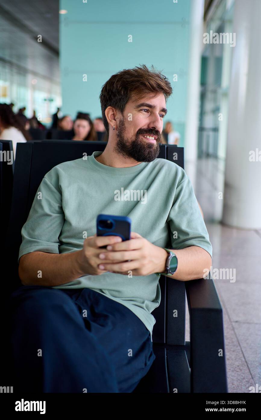 Smiling man using smartphone at airport gate Stock Photo