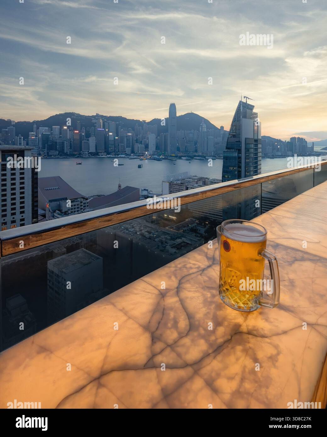 A Sunset View of Rooftop Bar & Glass of Beer overlooking Hong Kong City Skyline, Kowloon Stock Photo