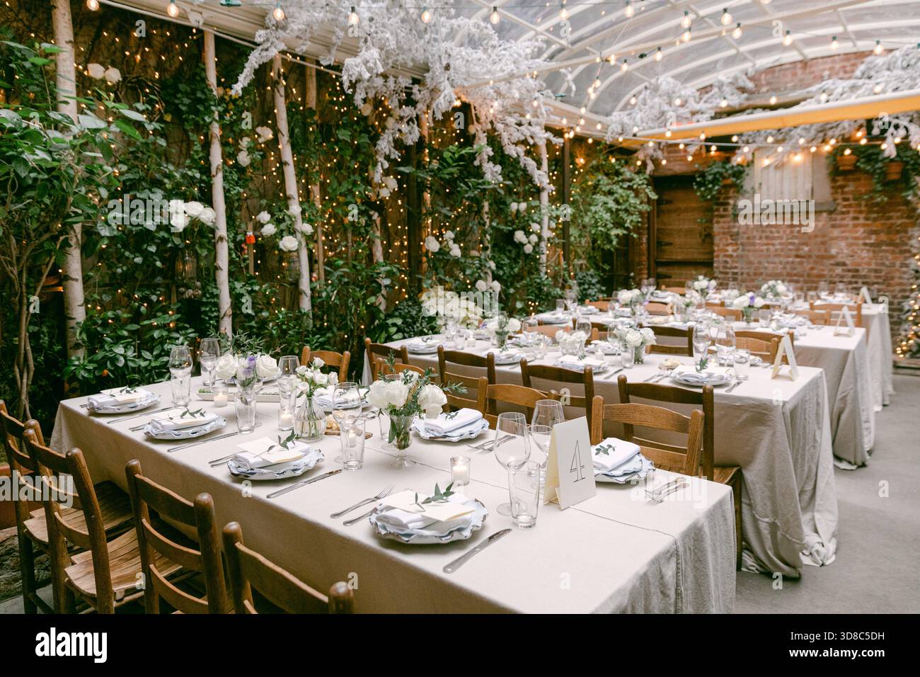 Tables are beautifully arranged with white flowers and decorations in a charming garden setting, perfect for gatherings. Stock Photo