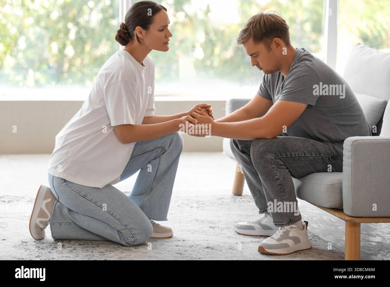 Young woman supporting sad man with suicidal thoughts at home Stock Photo