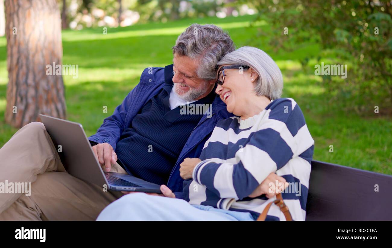 Senior couple using a laptop together in a park Stock Photo
