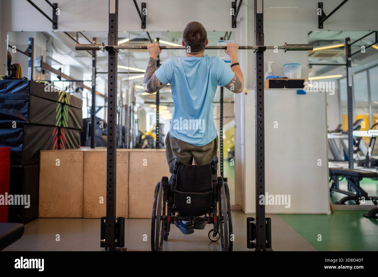 Disabled male sports. Rearview resilient man in wheelchair do pull up at gym to train upper body Stock Photo