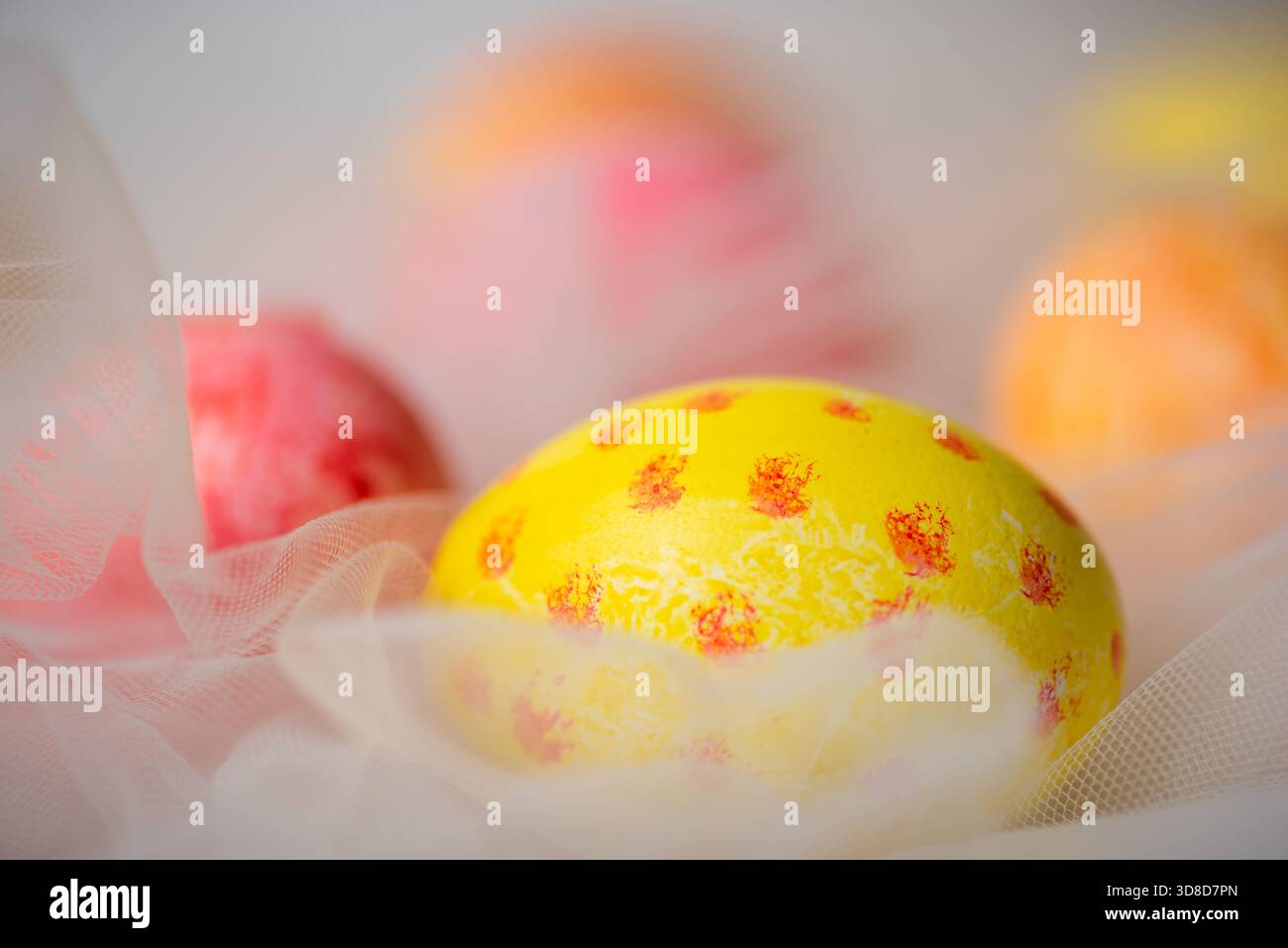 Hand painted pastel colored Easter eggs on white silky fabric closeup Stock Photo