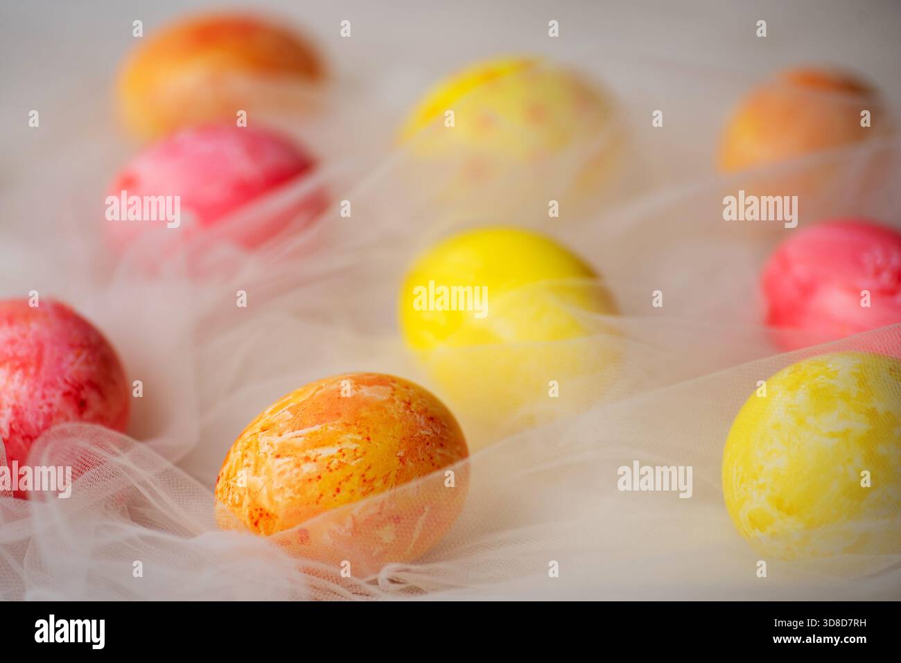 Hand painted pastel colored Easter eggs on white silky fabric closeup Stock Photo