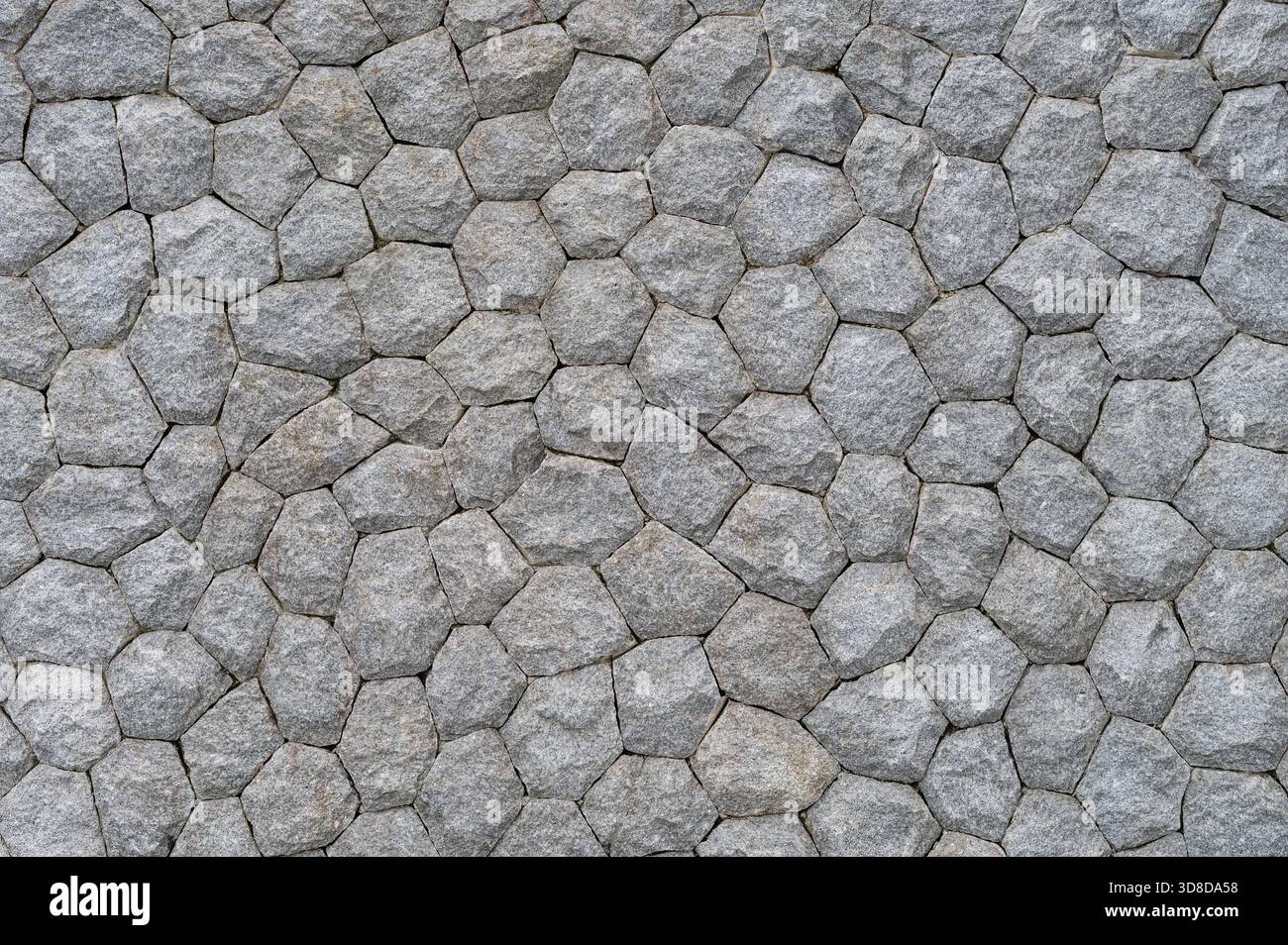 Textured gray stone wall with interlocking hexagonal pattern Stock Photo