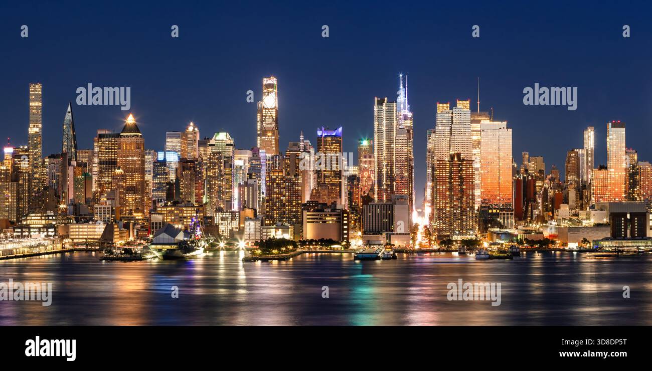 New York City elevated night view of Midtown Manhattan skyline, illuminated skyscrapers and the Hudson River Park waterfront piers. USA Stock Photo