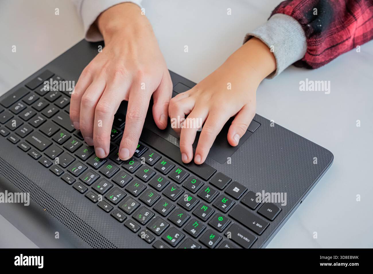 Adult Teaching Child to Type on Laptop Stock Photo