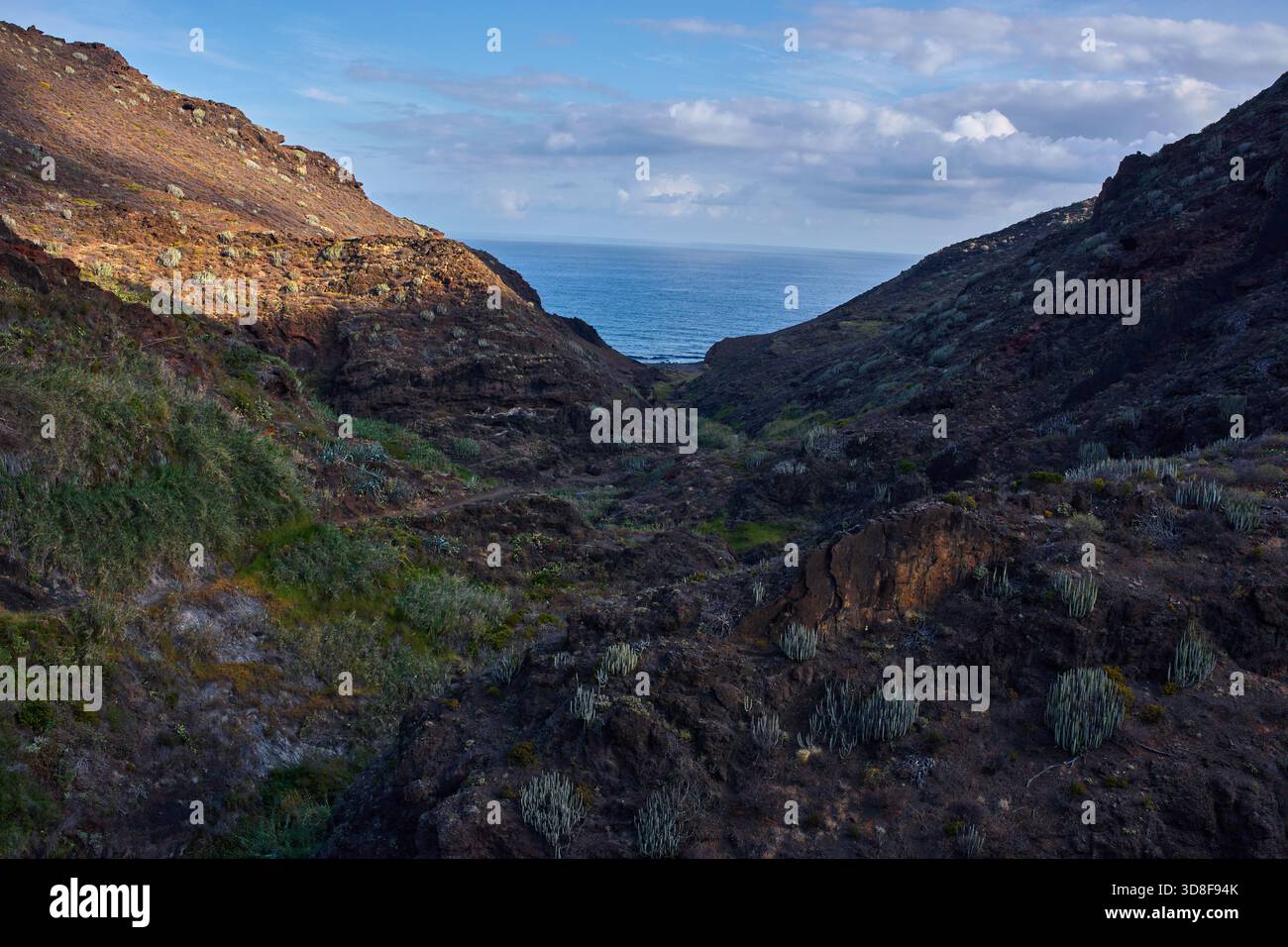 Hiking trail winding through volcanic ravine descending toward the ...