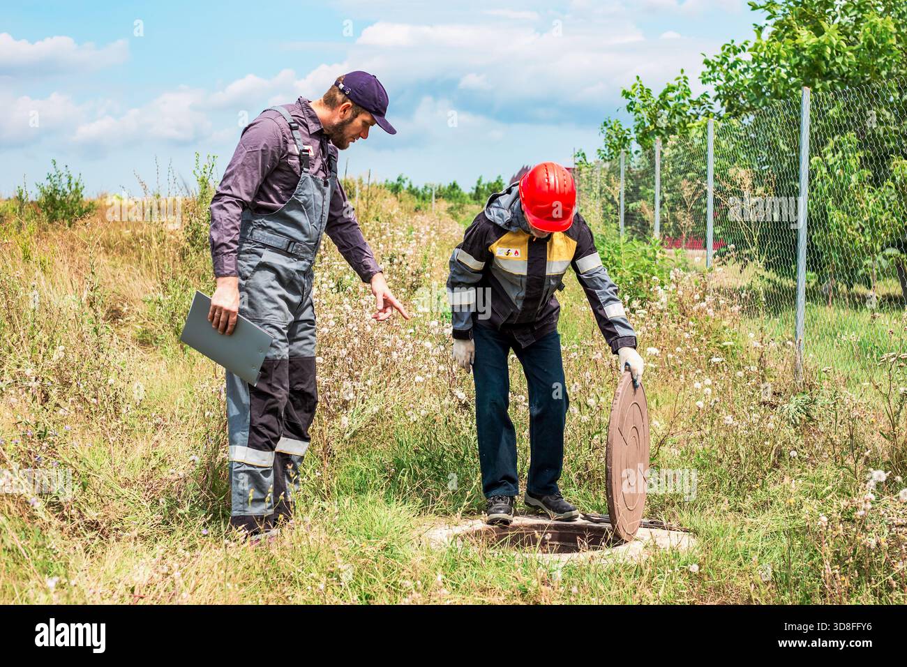 Municipal utility workers have opened a water well and are inspecting ...