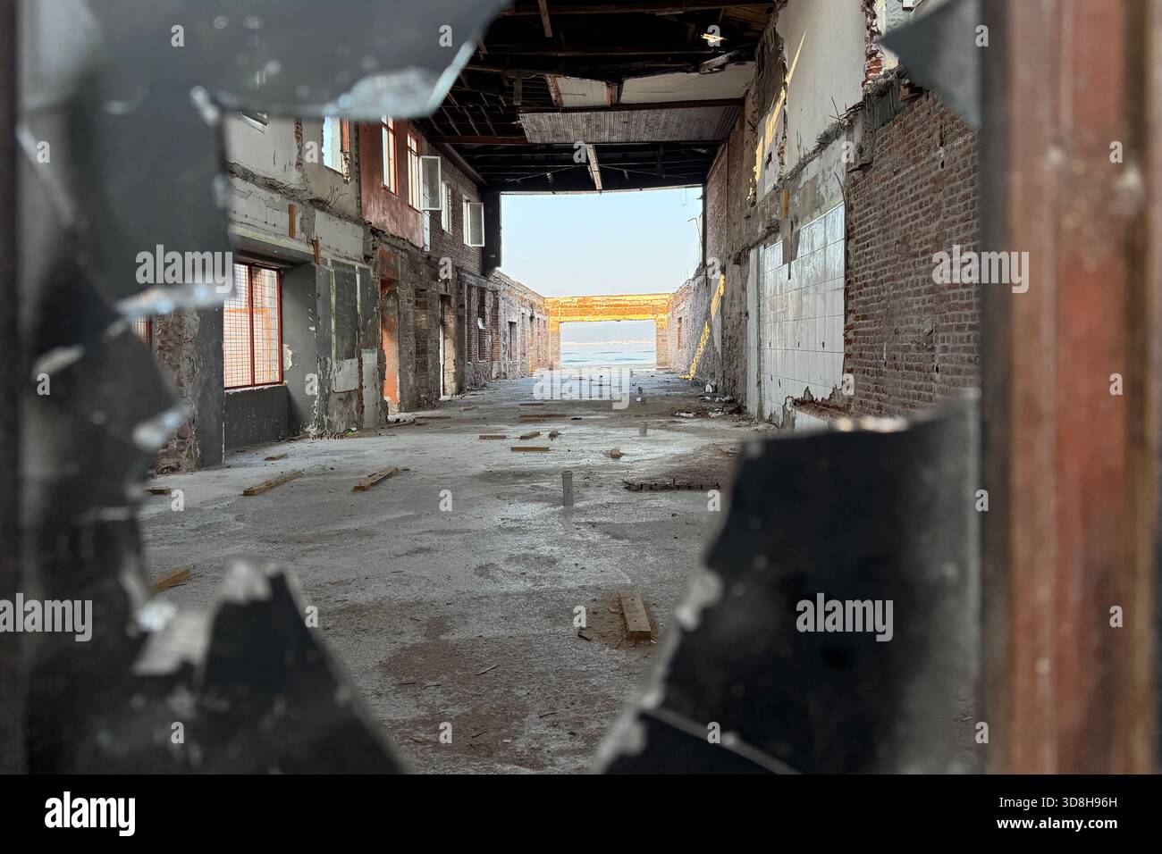 Empty ruins of a very heavily polluted industrial factory, abandoned empty building through burned black broken shattered glass, red stone tile wall Stock Photo