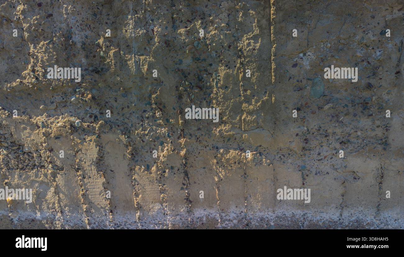 Rough, uneven concrete surface embedded with small pebbles and showing ...