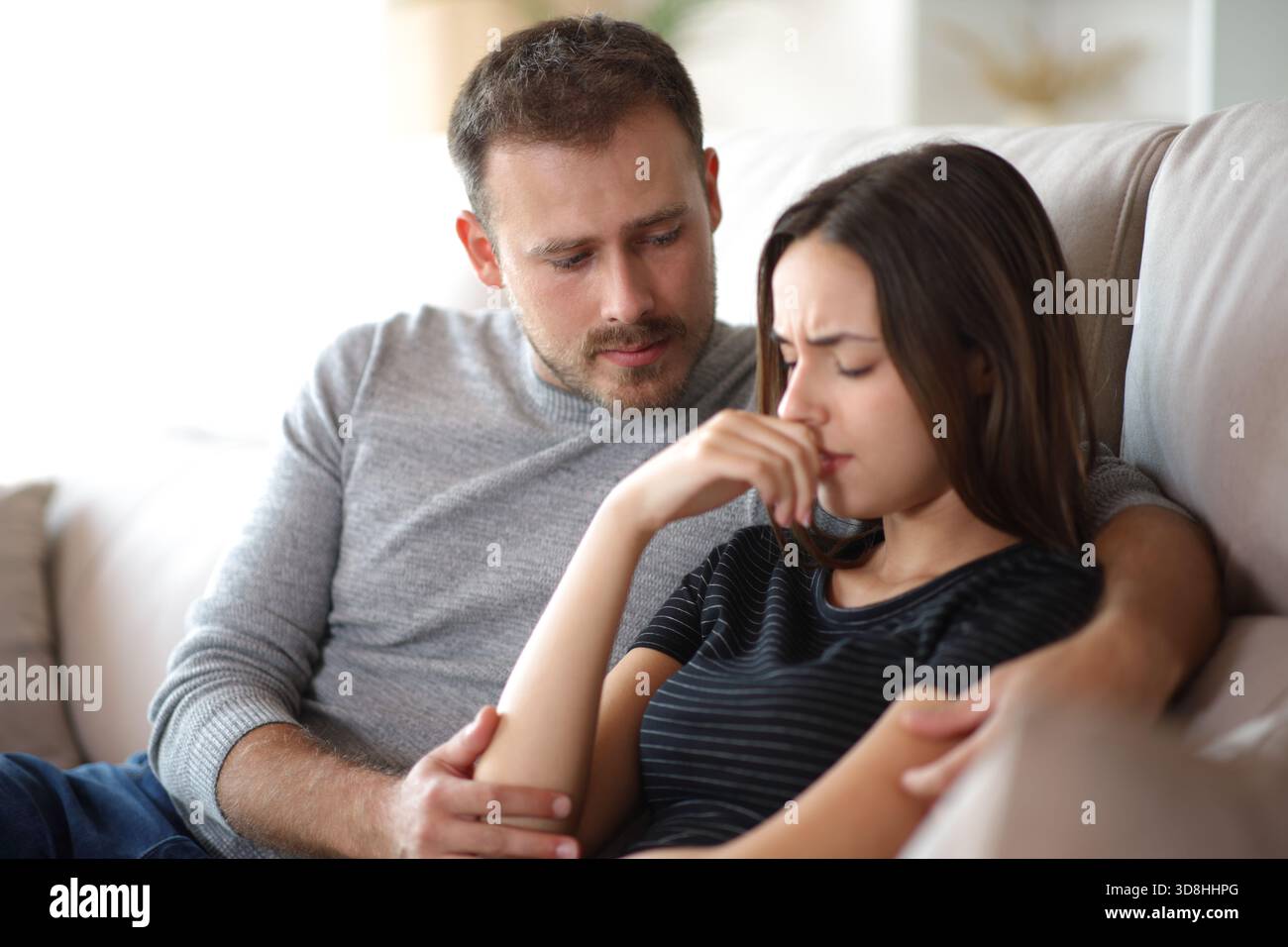 Man comforting sad woman sitting on a couch at home Stock Photo