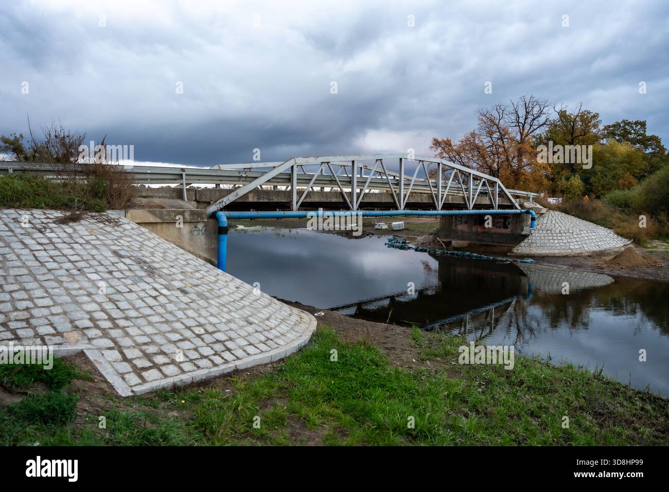 Steel Bridge Over Calm River With Sloped Concrete Embankment In Cloudy ...