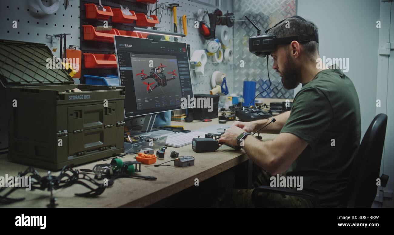Engineer Using VR Goggles to Virtually Design. Man in Military Style Uniform Utilizing VR Goggles and Computer While Assembling Drone Components. Concept Integration of Virtual Tools in Engineering. Stock Photo