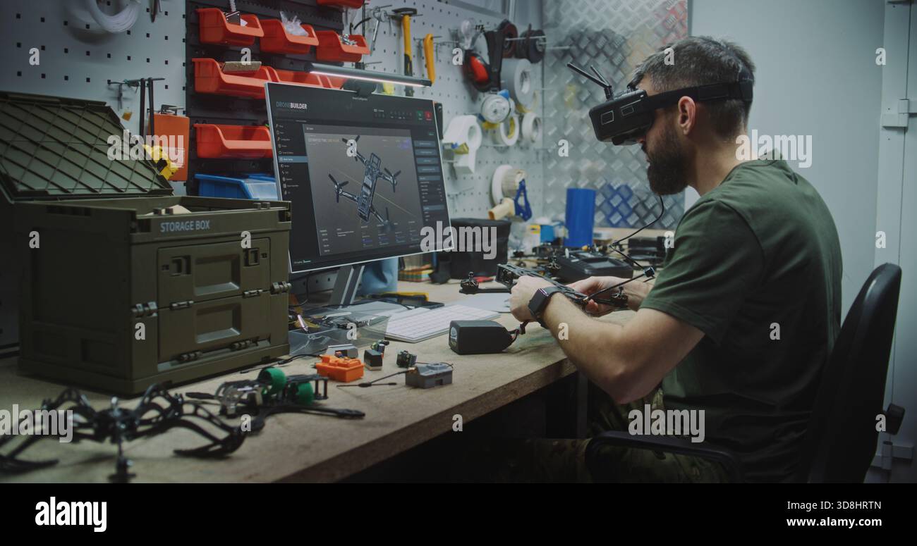 Engineer Using VR Goggles to Virtually Design. Man in Military Style Uniform Utilizing VR Goggles and Computer While Assembling Drone Components. Concept Integration of Virtual Tools in Engineering. Stock Photo