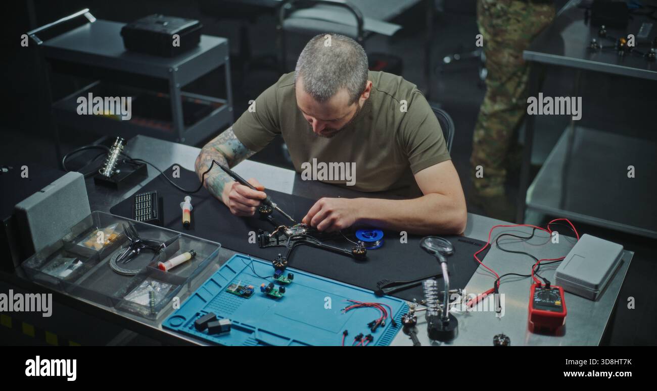 Concentrated Man Using Soldering Iron to Secure Microchips and Wiring ...