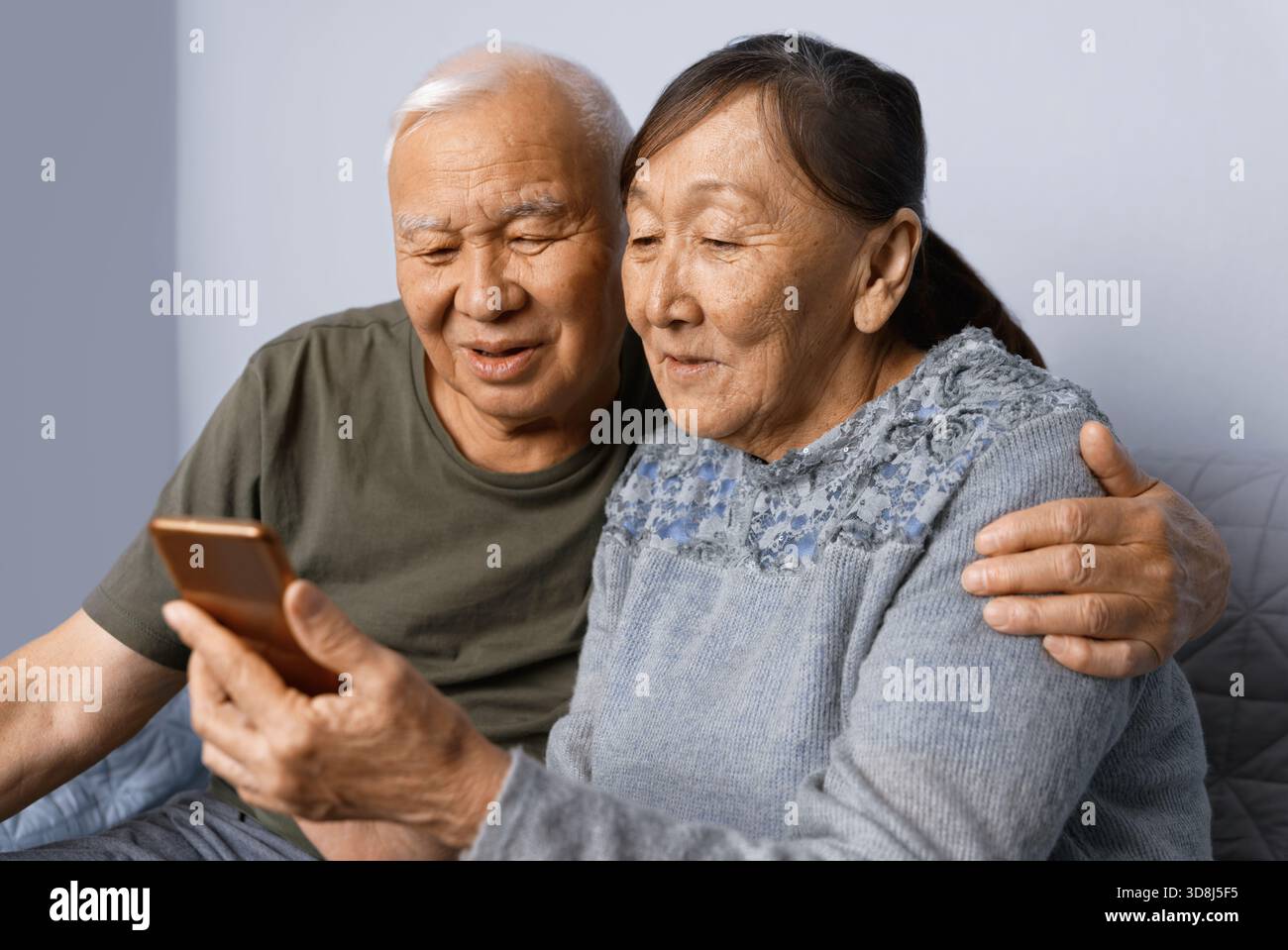Senior couple at home using smartphone Stock Photo