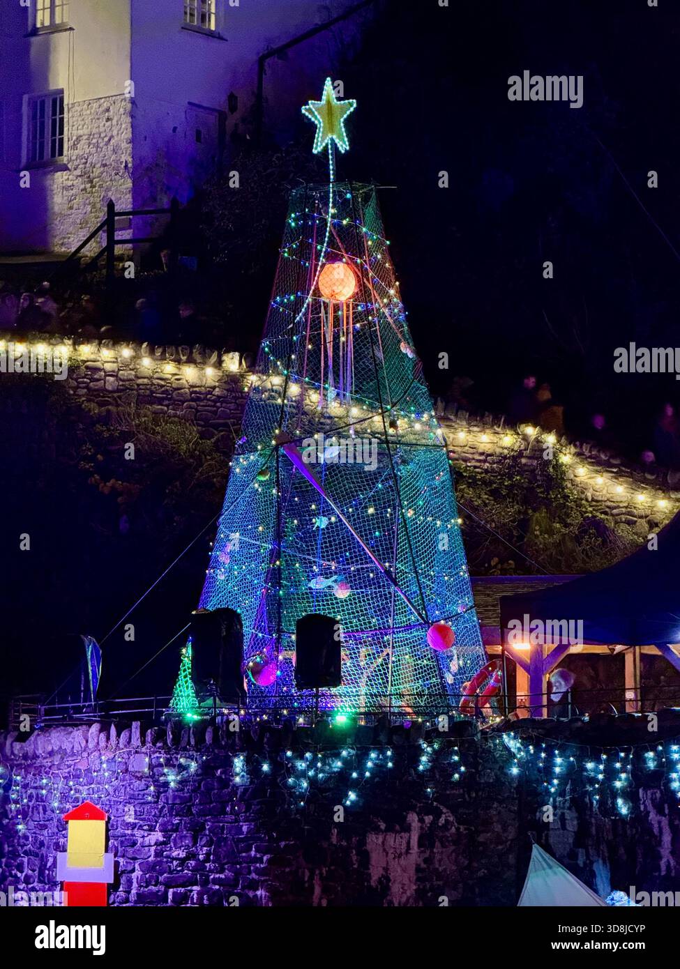 Clovelly’s harbour Christmas tree, made from fishing nets and floats, illuminated during the RNLI Christmas light switch on. - Smartphone Captured Stock Image