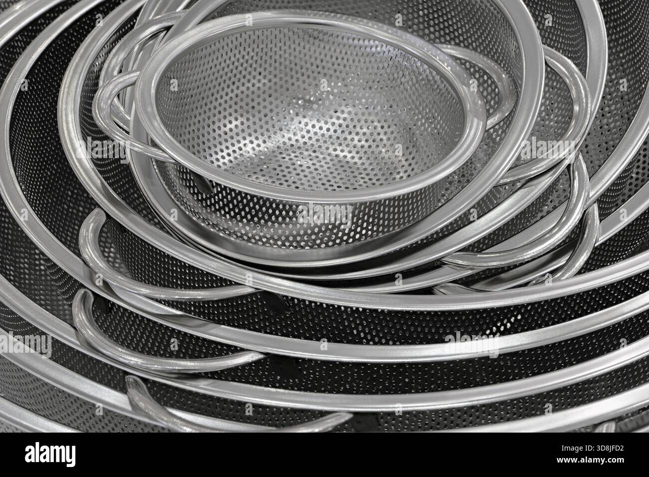 Group of round stainless steel collanders, various sizes, empty and clean, close-up shot, abstract background Stock Photo