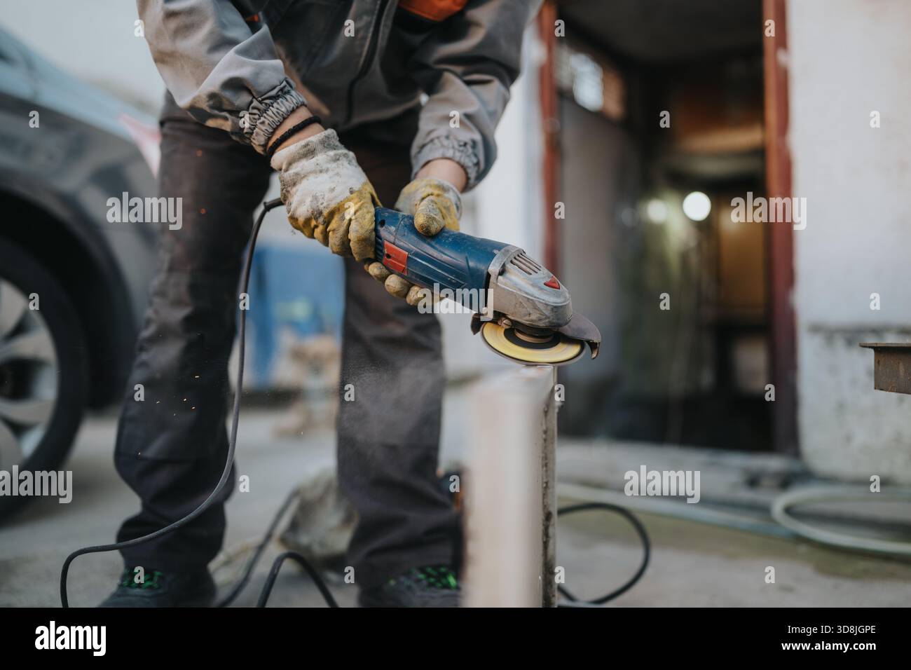 Worker uses angle grinder on metal, sparks fly during outdoor workshop  project Stock Photo - Alamy