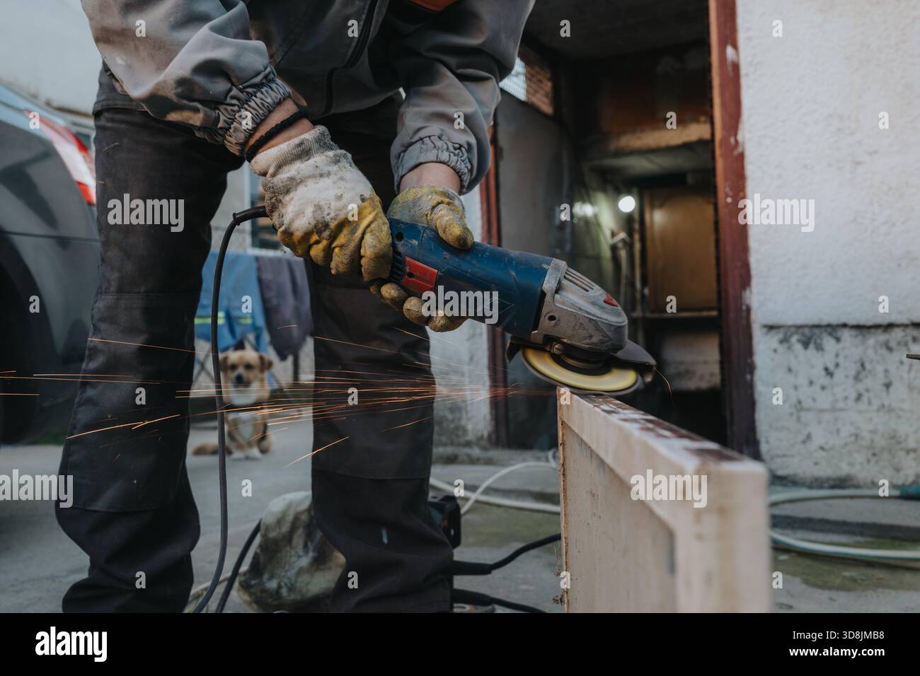 Worker uses angle grinder to cut metal beam outdoors with sparks and dog  nearby at a work site Stock Photo - Alamy