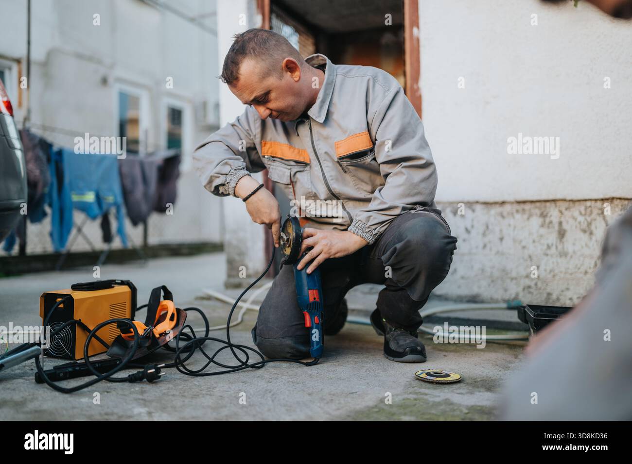 Construction worker using an angle grinder on an outdoor project with power tools and cables Stock Photo
