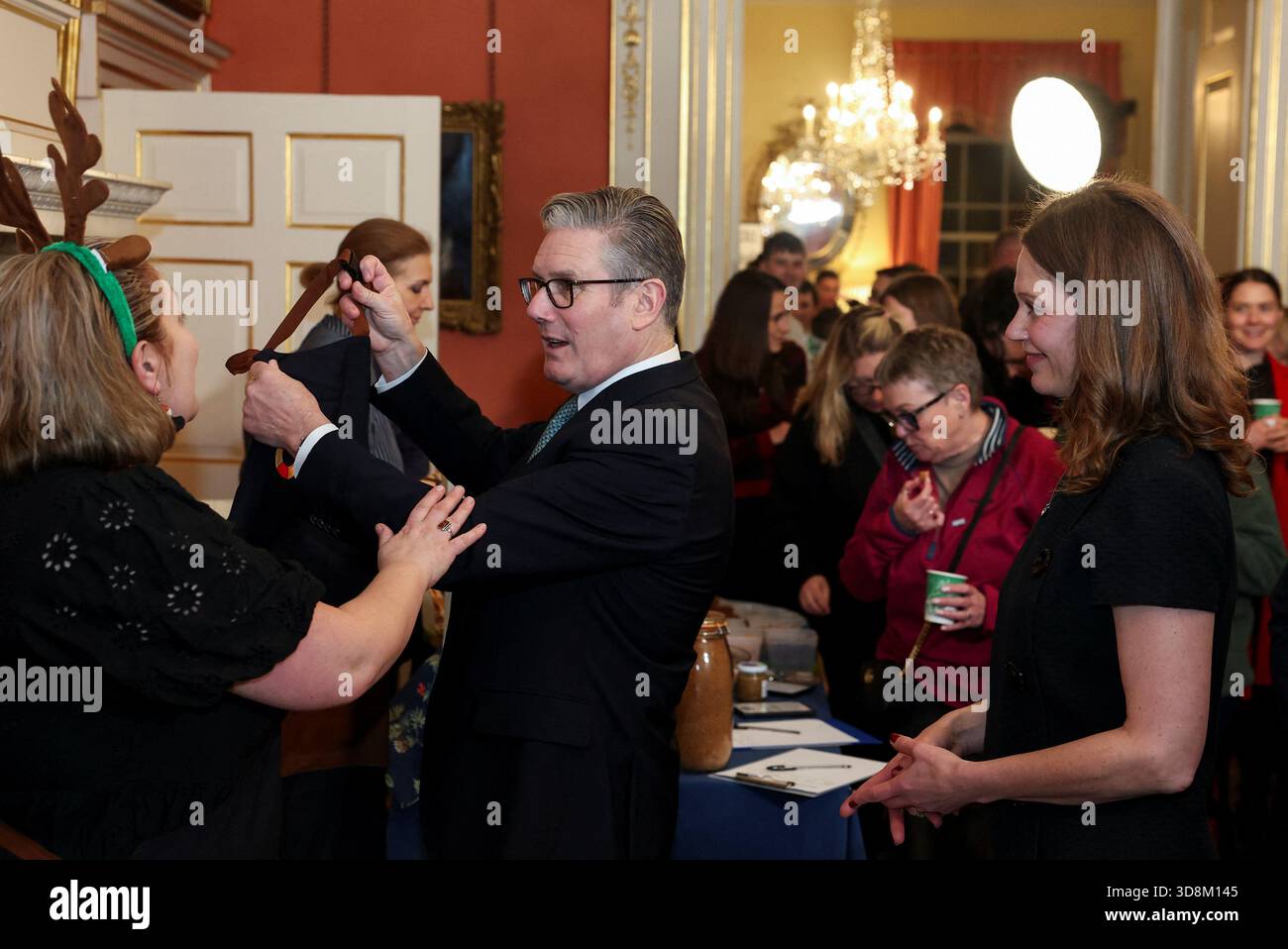 Prime Minister Sir Keir Starmer holds an apron watched by his wife Lady Victoria Starmer (right) as they host a Christmas market-style showcase for small firms and community champions in number 10 Downing Street, London. Picture date: Monday December 1, 2025. Stock Photo