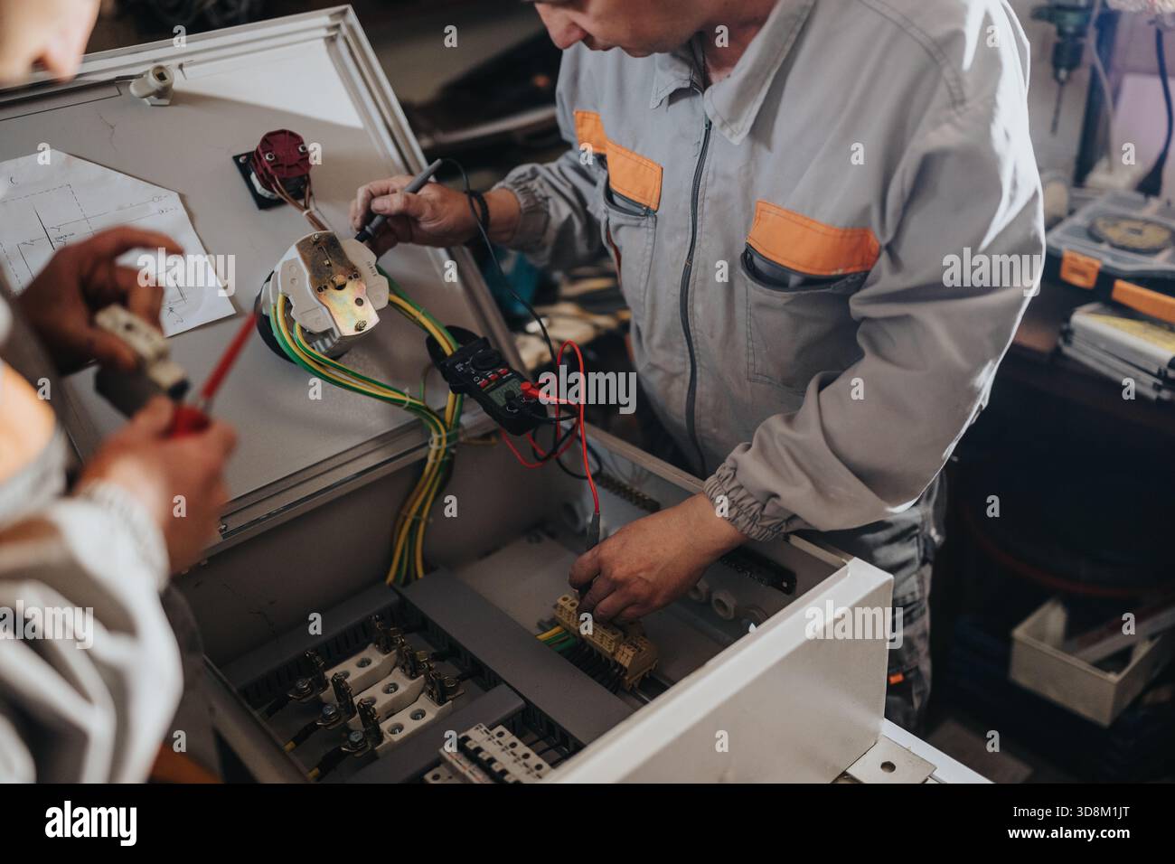 Technicians working on an electrical panel and wiring in a workshop, assembling and testing components Stock Photo