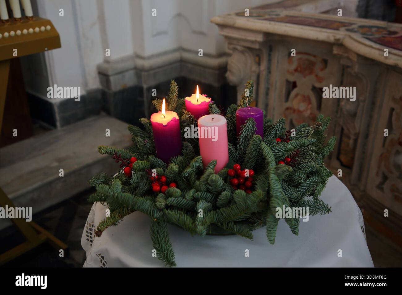 Candles from the Christmas preparation period lit inside the church of San Francesco di Paola at the beginning of Holy Mass. - Stock Image
