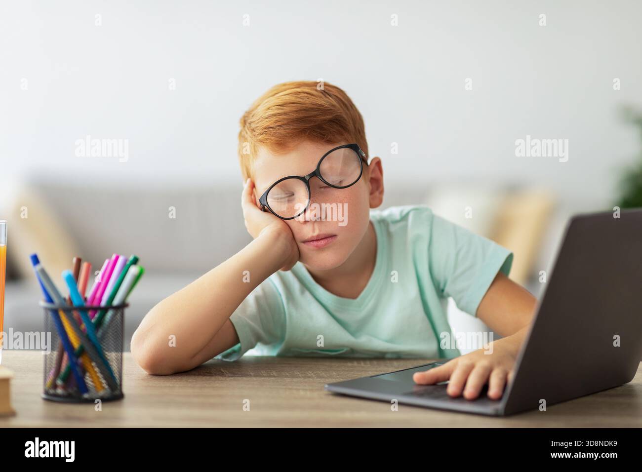 Exhausted Boy Falls Asleep While Doing Homework at the Desk During Study Time Stock Photo