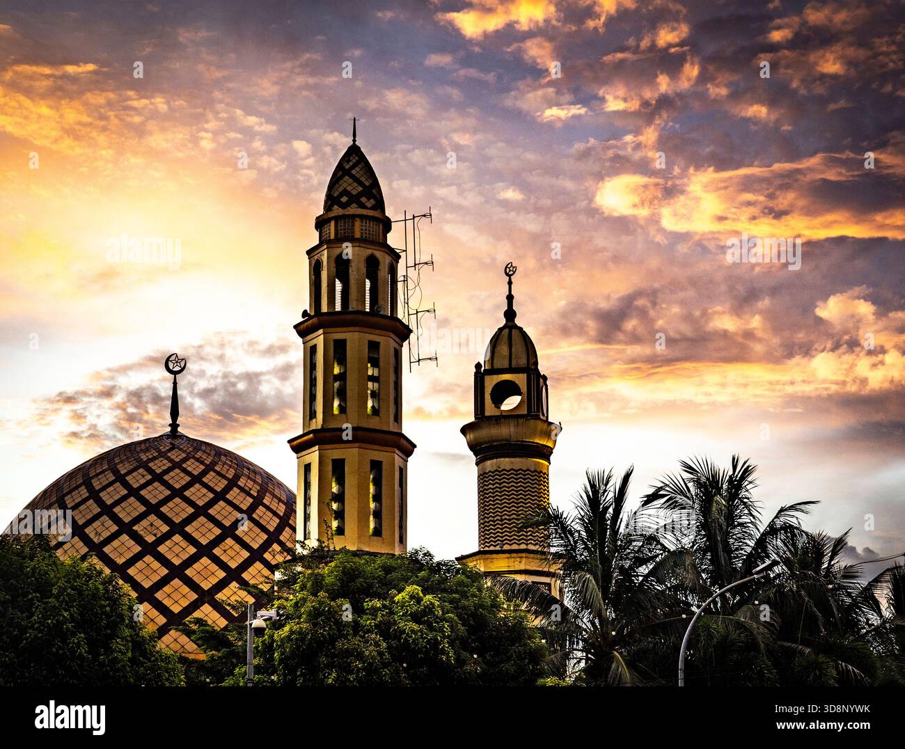 A mosque with two minarets against a dramatic sunset sky. Stock Photo