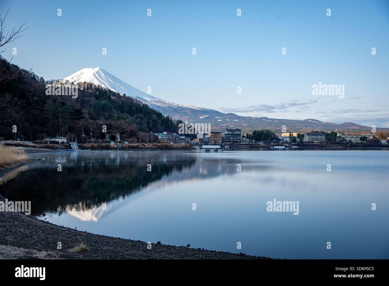 Mount Fuji rises over a calm lake with a clear reflection and soft ...