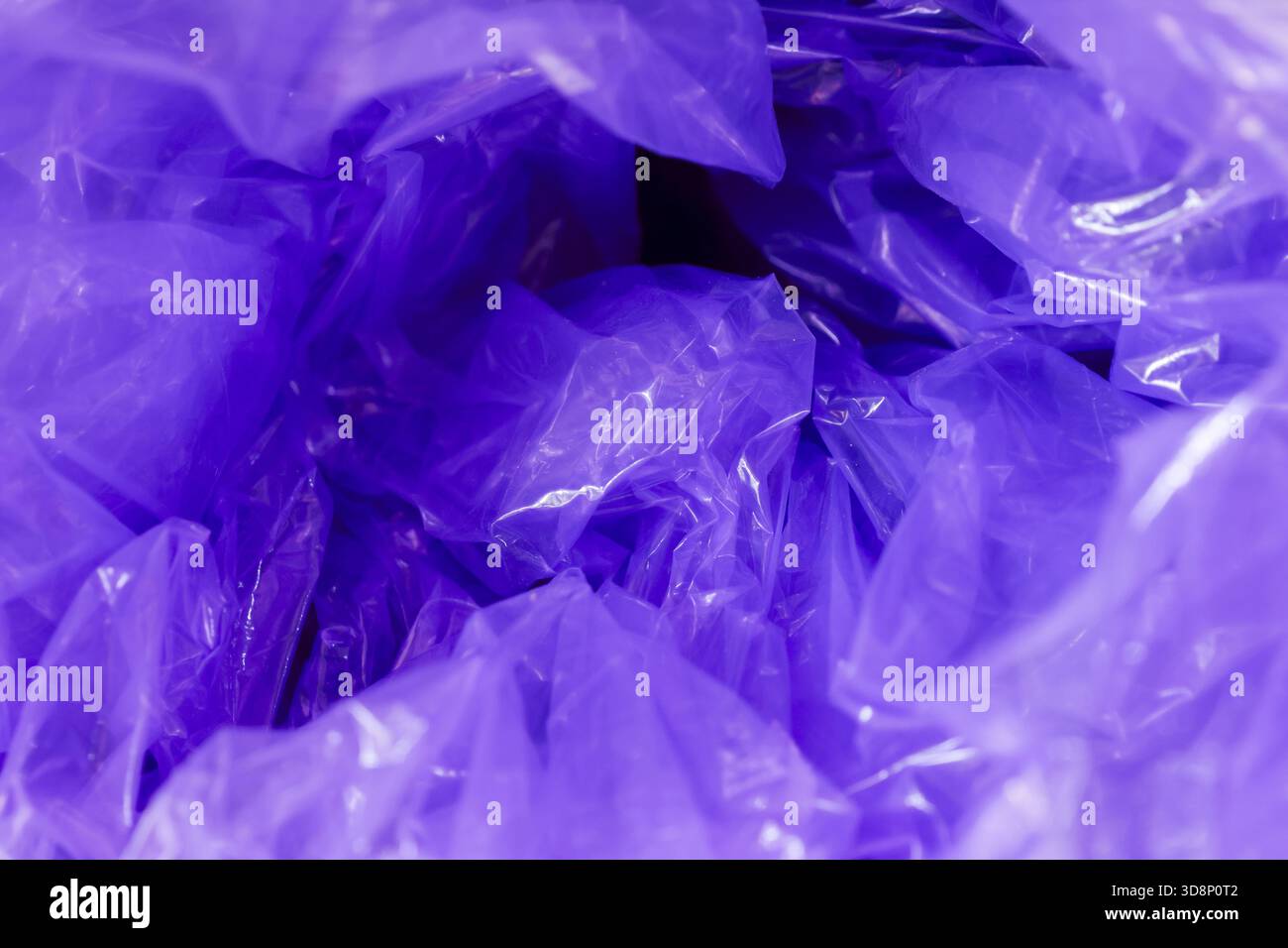 Macro view of crumpled purple plastic background creating chaotic abstract texture. shiny violet surface of wrapper reflects light, making dynamic and Stock Photo