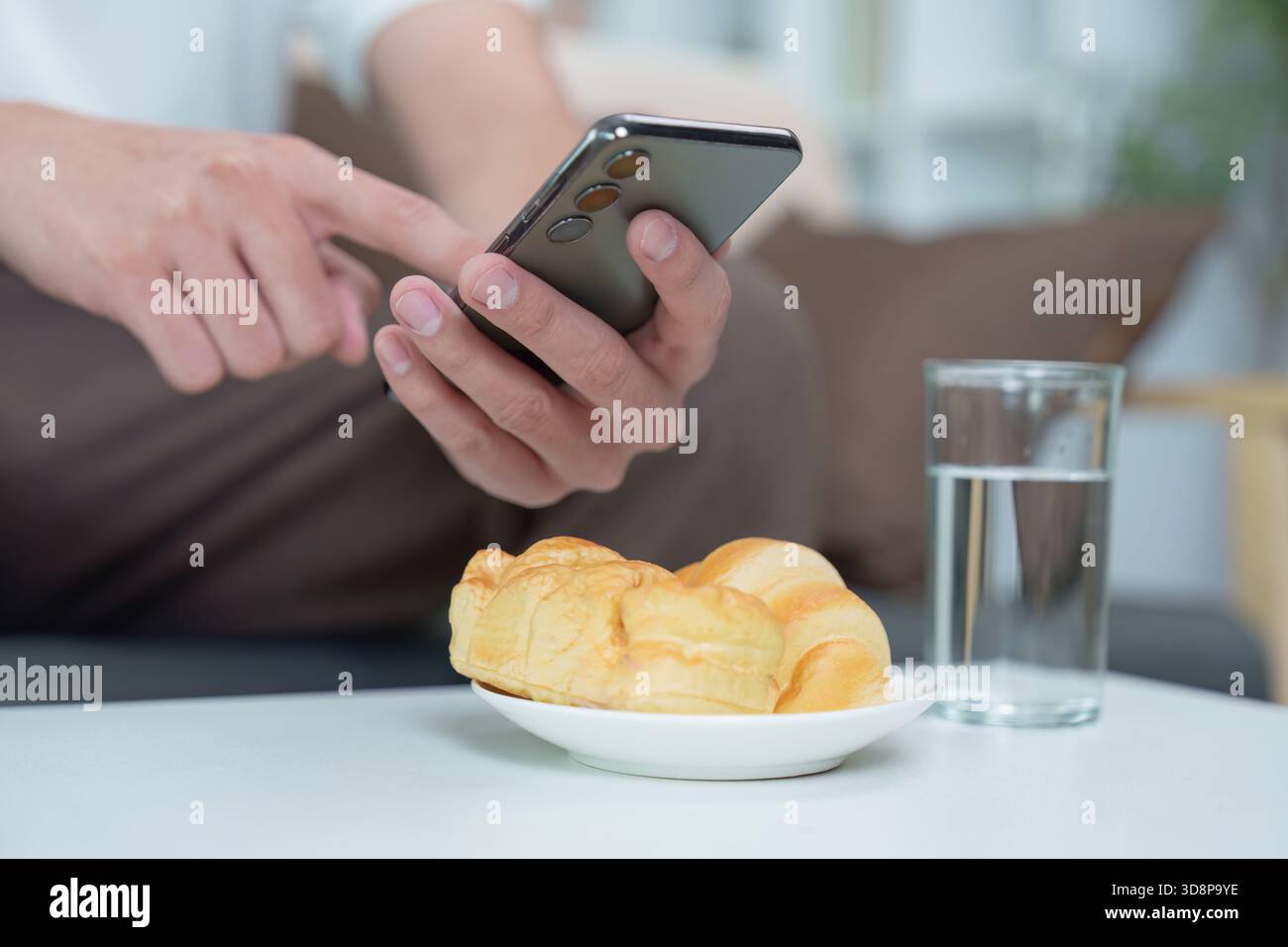 Technology and Lifestyle. Man using smartphone while enjoying breakfast. Stock Photo
