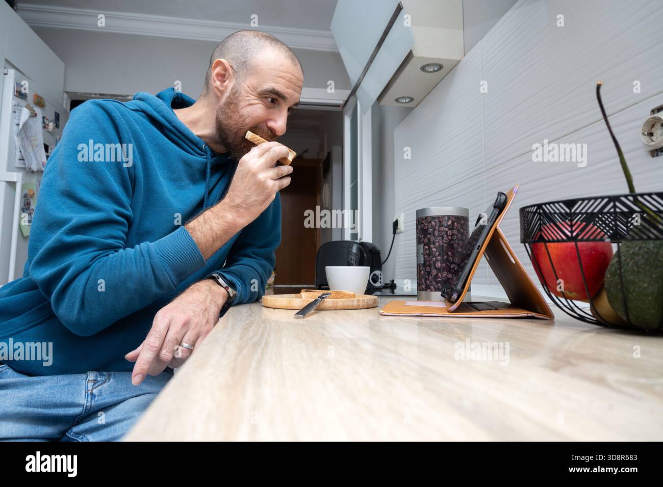 Man having toast for breakfast while using a tablet at home Stock Photo